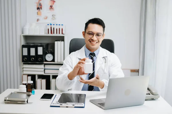 Attractive male doctor explaining medical treatment to patient through a video call in his office
