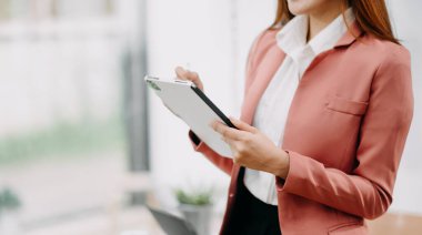 Ofisinde dijital tablet üzerinde çalışan kendine güvenen bir iş kadını.