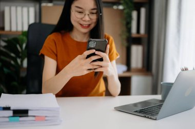 Cep telefonu kullanan bir kadın online alışveriş yapıyor, masada oturuyor.