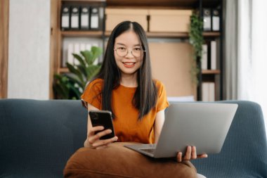 Asyalı kız kütüphanesi online bilgi aramak için dizüstü bilgisayarını kullanıyor.   