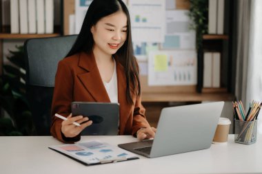 İş kadını ofis masasında dizüstü bilgisayar ve dijital tablet kullanarak finans raporu hazırlıyor. Ofiste analitik araştırma kavramı