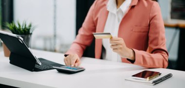 Akıllı telefon kullanan bir kadın. İnternet üzerinden alışveriş yapmak için kredi kartı ve tablet bilgisayar kullanıyor.