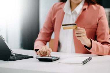 Cep telefonu kullanan bir kadın online alışveriş yapıyor, masada oturuyor.