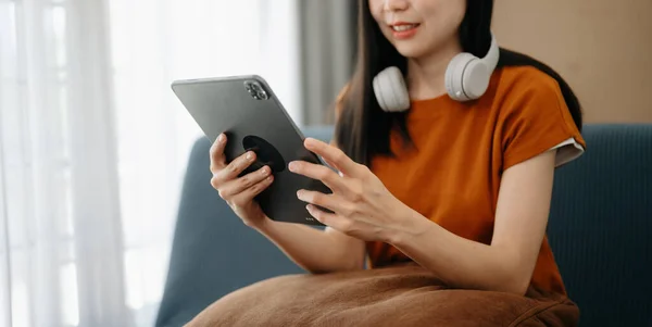 Woman using tablet for mobile payments online shopping, sitting on table