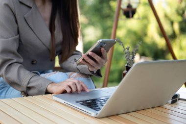 Akıllı telefon ve dizüstü bilgisayar kullanan bir iş kadını. Bulanık arkaplanda yakın plan
