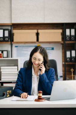 Asyalı kadın avukat müşteriyle internette sohbet ediyor, dava detaylarını tartışıyor. Modern ofiste akıllı telefondan.