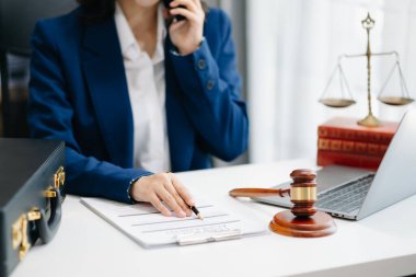 Asyalı kadın avukat müşteriyle internette sohbet ediyor, dava detaylarını tartışıyor. Modern ofiste akıllı telefondan.