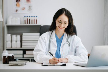 Güzel doktor modern ofis hastanesinde masada oturuyor. Çekici terapist gülümse ve dizüstü bilgisayar kullan