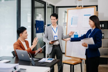 Patron grafiklerle kurulun yanında duruyor, istatistikleri gösteriyor, eğitime katılan çeşitli personel, şirketin yeni ürünlerini ofiste tanıtıyor.