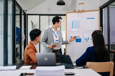 Bir grup Asyalı iş adamı modern yaratıcı ofiste iş planlarını tartışıyor.