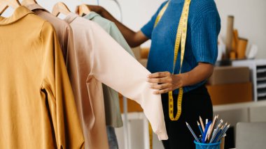 The designer is measuring the shirt fashion working on her designs in the studio clipart