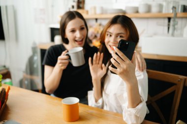 İki Asyalı öğrenci mutfaktaki akıllı telefondan ya da evdeki oturma odasından birlikte öğreniyor..