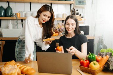 Evde yemek yapan bir çift resmi. Genç kadınlar sıcak mutfakta birlikte yemek pişiriyorlar.