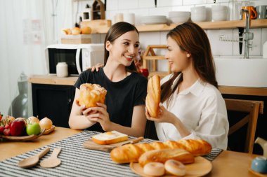 Evde yemek yapan bir çift resmi. Genç kadınlar sıcak mutfakta birlikte yemek pişiriyorlar.