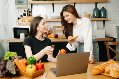 Evde yemek yapan bir çift resmi. Genç kadınlar sıcak mutfakta birlikte yemek pişiriyorlar.