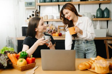 Evde yemek yapan bir çift resmi. Genç kadınlar sıcak mutfakta birlikte yemek pişiriyorlar.