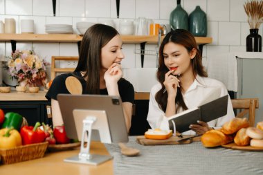Mutfakta önlüklü iki güzel kadın, masaya taze sebzeler, en sevdiği tarifleri yazıyorlar, yemek için fikirler üretiyorlar. 