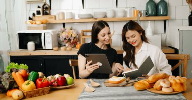 Mutfakta önlüklü iki güzel kadın, masaya taze sebzeler, en sevdiği tarifleri yazıyorlar, yemek için fikirler üretiyorlar. 