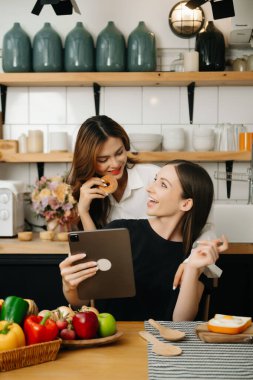 Evde yemek yapan bir çift resmi. Genç kadınlar sıcak mutfakta birlikte yemek pişiriyorlar.