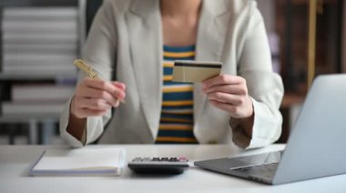 İş kadını, internet üzerinden alışveriş yapmak için kredi kartıyla hesap makinesi ve ofis içi finans stratejisi kullanıyor..