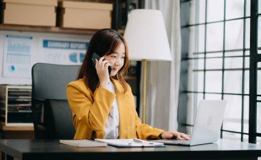 İş kadını akıllı telefon ve dizüstü bilgisayarını ofis masasında finans raporu olarak kullanıyor. Ofiste analitik araştırma kavramı