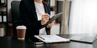 Ofisinde dijital tablet üzerinde çalışan kendine güvenen bir iş kadını.