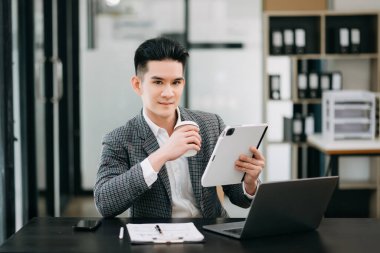 Olgun iş adamı yöneticisi dijital tablete bakıyor, çevrimiçi webinar eğitimi izliyor veya sanal toplantı video konferansı yapıyor, pazar araştırması yapıyor, ofiste çalışıyor.