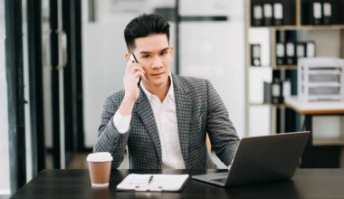 Olgun iş adamı yöneticisi akıllı telefon kullanır, piyasa araştırması yapar, ofiste çalışır.