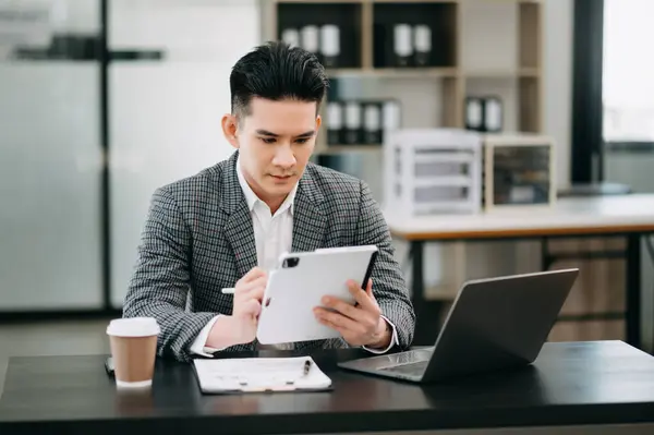 Mature businessman executive manager looking at digital tablet, watching online webinar training or having virtual meeting video conference, doing market research, working in office