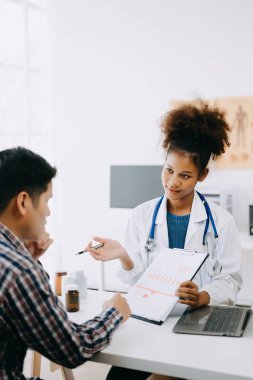 Afrikalı doktor ve Asyalı hasta masada otururken bir şey tartışıyorlar. İlaç ve sağlık hizmetleri kavramı.