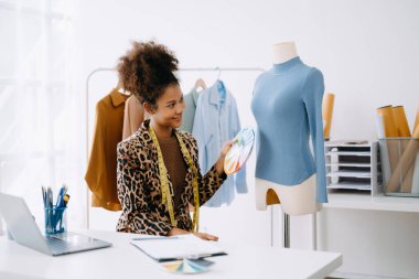 Afrikalı terzi kadın terzide terzilik yapıyor. Güzel genç bayan moda tasarımcısı gülümsemesi ve stüdyo başarısından sonra