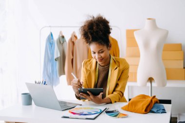 Afrikalı terzi kadın terzide terzilik yapıyor. Güzel genç bayan moda tasarımcısı gülümsemesi ve stüdyo başarısından sonra