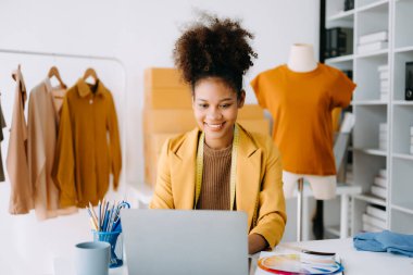 Afrikalı terzi kadın terzide terzilik yapıyor. Güzel genç bayan moda tasarımcısı gülümsemesi ve stüdyo başarısından sonra