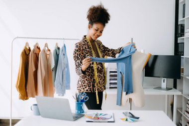 Afrikalı terzi kadın terzide terzilik yapıyor. Güzel genç bayan moda tasarımcısı gülümsemesi ve stüdyo başarısından sonra