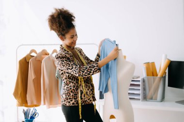 Sakin, kıvırcık esmer, esmer, esmer kadın moda tasarımcısının modern ofisinde çalışıyor. 