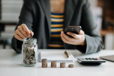 Ofisinde akıllı telefon kullanan, camlı sikkeleri olan bir iş kadını.