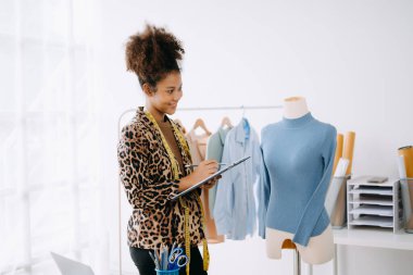 Afrikalı terzi kadın terzide terzilik yapıyor. Güzel genç bayan moda tasarımcısı gülümsemesi ve stüdyo başarısından sonra