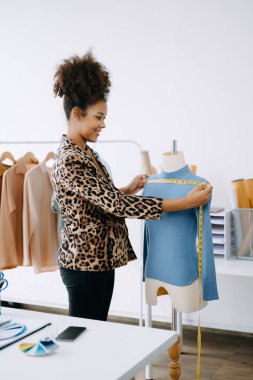Afrikalı terzi kadın terzide terzilik yapıyor. Güzel genç bayan moda tasarımcısı gülümsemesi ve stüdyo başarısından sonra