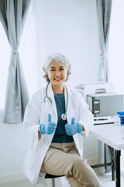 Asian smiling doctor or consultant sitting at a desk his looking at the camera