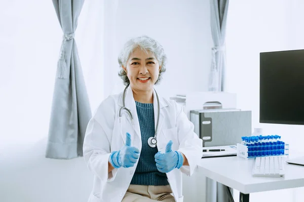 Asian smiling doctor or consultant sitting at a desk his looking at the camera