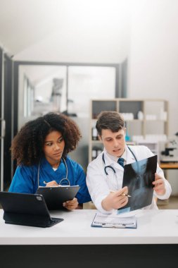  Doktor, profesyonel baş hemşire ya da cerrahla konuşuyor. Dijital tablet bilgisayar kullanıyorlar. Muhtelif sağlık uzmanları test sonuçlarını hastanede masasında tartışıyor.