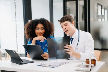 Yetişkin erkek doktor ve Afrikalı kadın hemşire birlikte anesteziyi tartıştılar. Hastanedeki çeşitli tıp uzmanları...