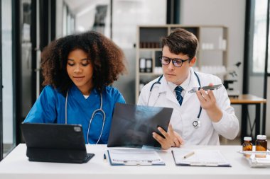  Doktor, profesyonel baş hemşire ya da cerrahla konuşuyor. Dijital tablet bilgisayar kullanıyorlar. Muhtelif sağlık uzmanları test sonuçlarını hastanede masasında tartışıyor.
