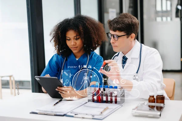 Doctor Talks With Professional Head Nurse or Surgeon, They Use Digital tablet Computer. Diverse Team of Health Care Specialists Discussing Test Result on desk in hospital