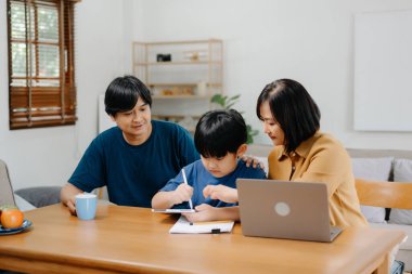 Tahta masada oğlunun ödevlerini yapmasına yardım eden ebeveynler..