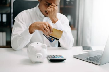 Finansal borç, Asyalı bir adamın oturması, kredi kartı tutması, fatura veya fatura giderlerinin hesaplanmasıyla vurgulanması.