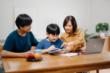 Tahta masada oğlunun ödevlerini yapmasına yardım eden ebeveynler..
