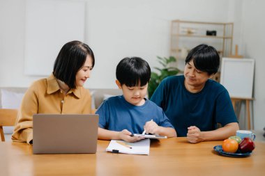 Tahta masada oğlunun ödevlerini yapmasına yardım eden ebeveynler..