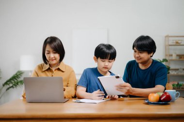 Tahta masada oğlunun ödevlerini yapmasına yardım eden ebeveynler..