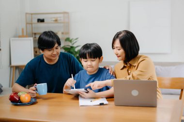 Tahta masada oğlunun ödevlerini yapmasına yardım eden ebeveynler..